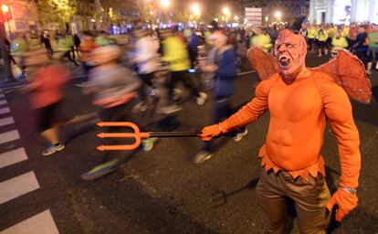 Un hombre disfrazado de diablo al paso de los corredores de la San Silvestre Vallecana, en 2014.