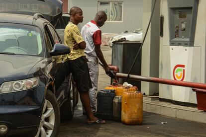 Dos hombres llenando recipientes con combustible, en una gasolinera de Lagos. 