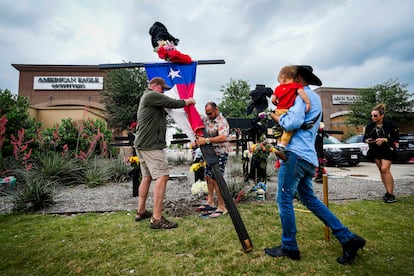 Residents raise a cross with a Texas flag as they construct a memorial outside an entrance to the mall a day after a mass shooting at Allen Premium Outlets on May 7, 2023, in Allen, Texas.