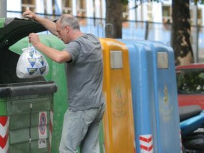 Una persona diposita una bossa d'escombraries en un contenidor a Sant Sebastià.