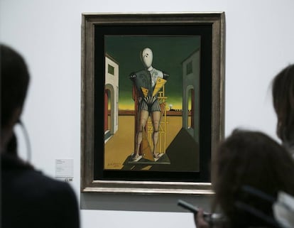 Varios visitantes observan el cuadro 'El Trovador' (1972) en el que aparece un maniquí que posa en un espacio que se asemeja a la plaza de Italia de París, recurso arquitectónico recurrente en la obra del artista.