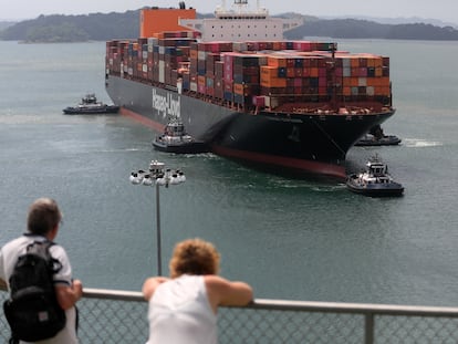 Dos personas observan un buque de carga en el Canal de Panamá en enero.