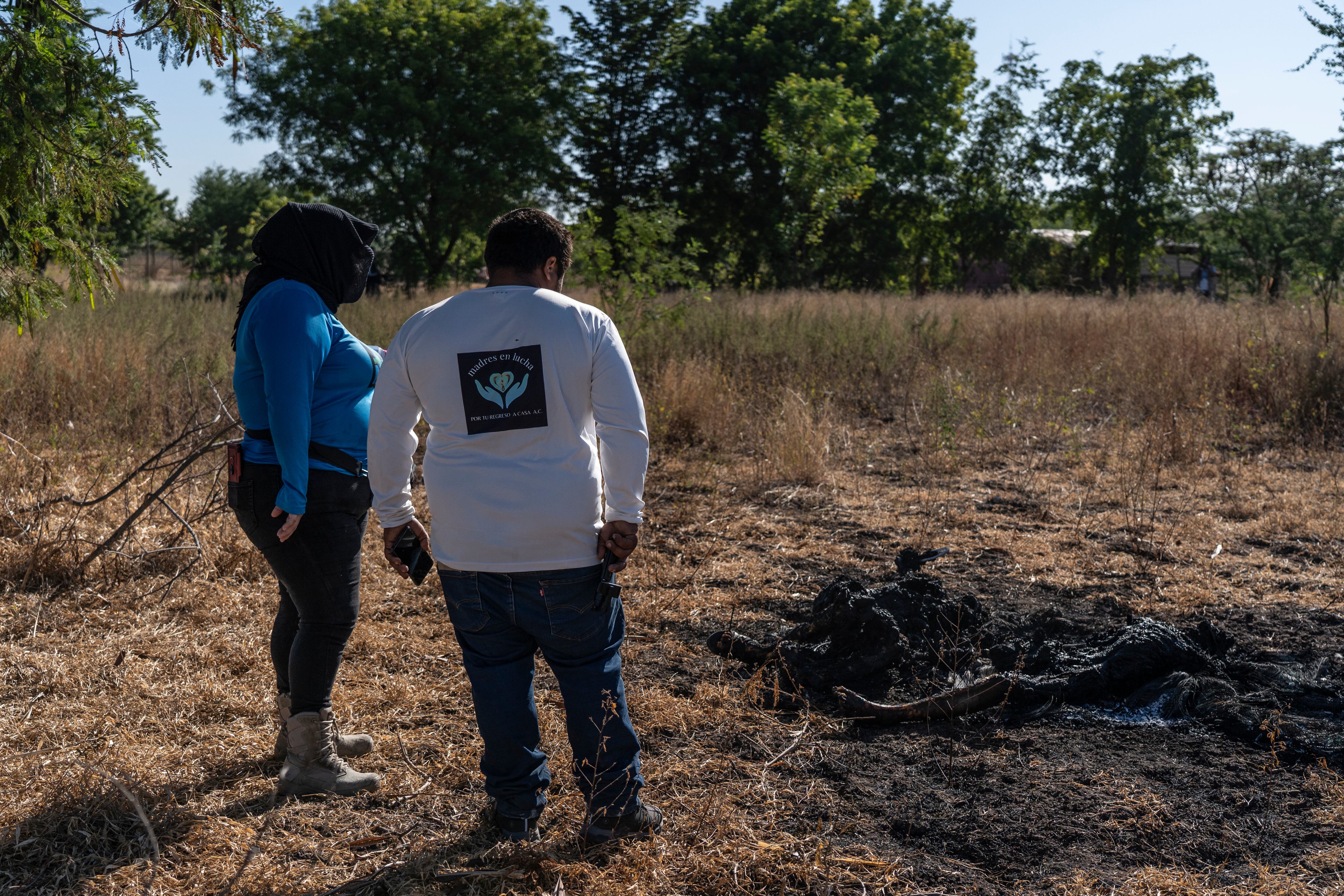 Reinalda Pulido y su hijo observan los cuerpos de dos personas calcinadas en la sindicatura de Costa Rica, Culiacán.