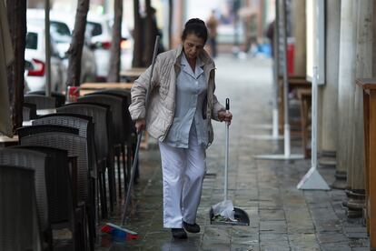Una trabajadora de una empresa de limpieza barre el suelo de la terraza de un bar de Sevilla, en una imagen de archivo.