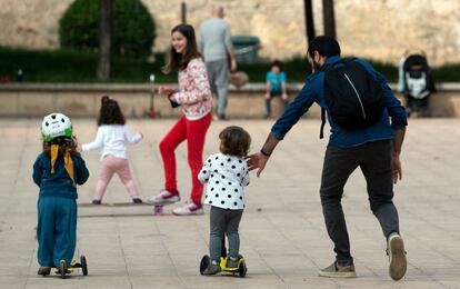 Um pai segura a sua filha que brinca com em patinete, em Valência.