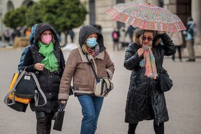 Varias personas pasean abrigadas por el centro de Valencia este lunes a causa de las temperaturas inusualmente bajas.