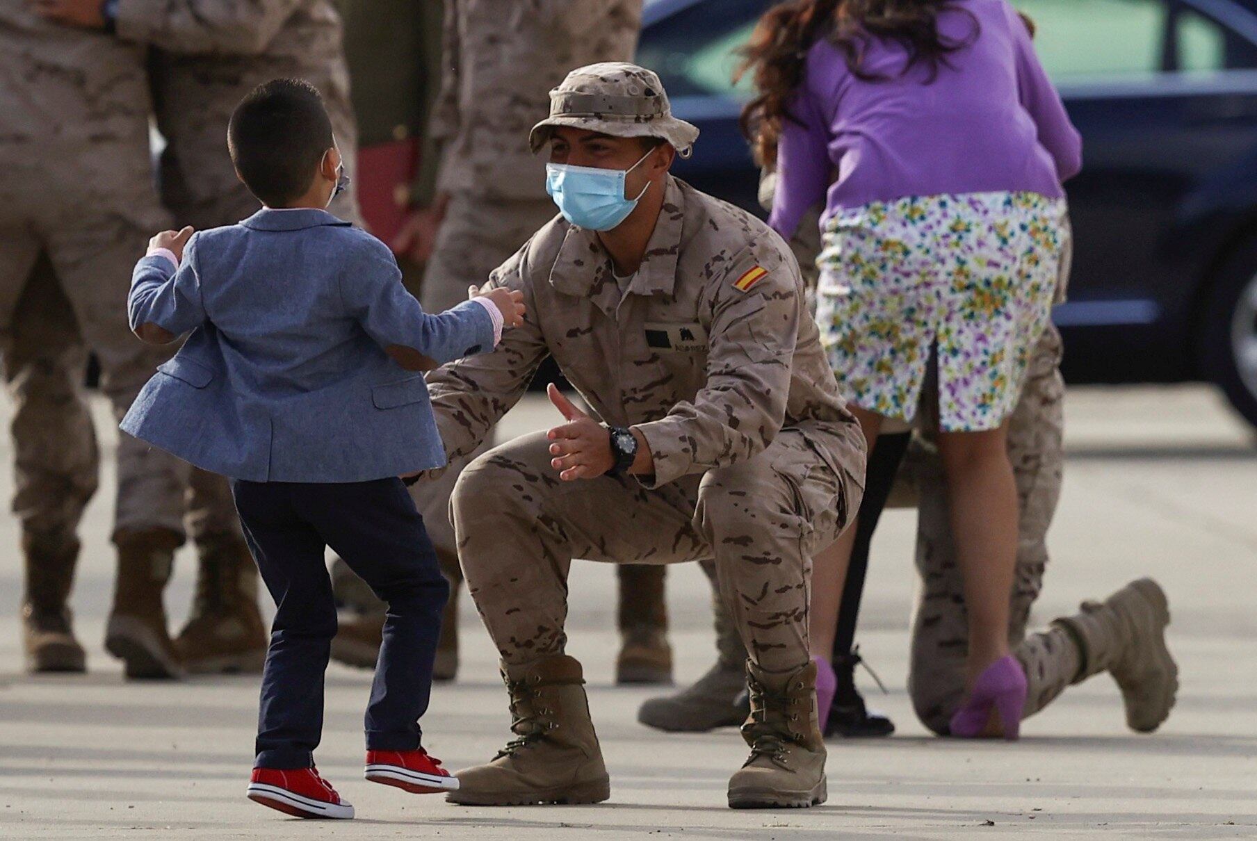 Uno de los militares españoles llegados de Afganistán abraza a un niño que ha acudido a recibirlo en la base de Torrejón de Ardoz, 