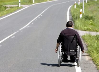 Una persona en silla de ruedas transita por una carretera a las afueras de Vitoria.