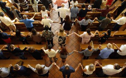 Los feligreses se cogen de las manos mientras cantan durante un servicio matutino en la Iglesia de San Pío X en El Paso, Texas, el domingo 4 de agosto de 2019. 
