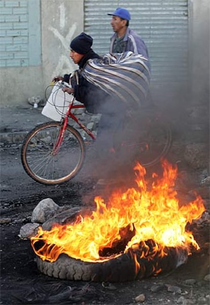 Habitantes de El Alto pasan junto a un neumático en llamas.