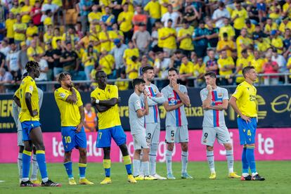 Los jugadores del Cádiz y el Barcelona, esperan en el campo tras el problema médico de un aficionado en la grada.