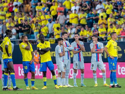 Los jugadores del Cádiz y el Barcelona, esperan en el campo tras el problema médico de un aficionado en la grada.