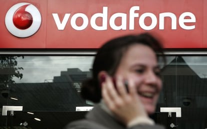 Una mujer habla por tel&eacute;fono frente a una tienda de Vodafone.