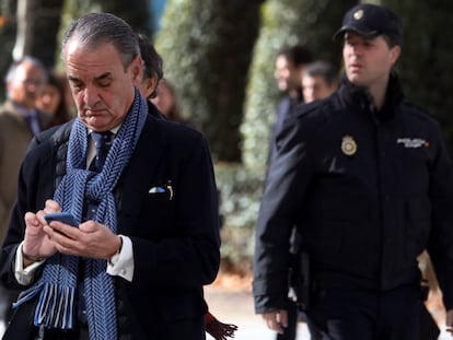 Mario Conde consulta su teléfono móvil a la salida de la Audiencia Nacional, en Madrid.