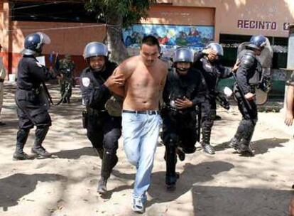 Agentes de la Unidad del Mantenimiento del Orden (UMO) de la Policía custodian a un reo de la cárcel de Apanteos, en el oeste de El Salvador, tras la matanza que se ha producido en el centro penitenciario, en la que han muerto al menos 17 presos.