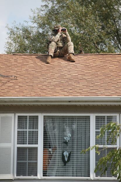 FOX LAKE, IL - SEPTEMBER 01: A police sniper keeps watch from the roof of a home while other police search nearby for suspects involved in the shooting of an officer September 1, 2015 in Fox Lake, Illinois. A manhunt for three suspects is underway after an officer from Fox Lake Police was shot and killed this morning.   Scott Olson/Getty Images/AFP
== FOR NEWSPAPERS, INTERNET, TELCOS & TELEVISION USE ONLY ==