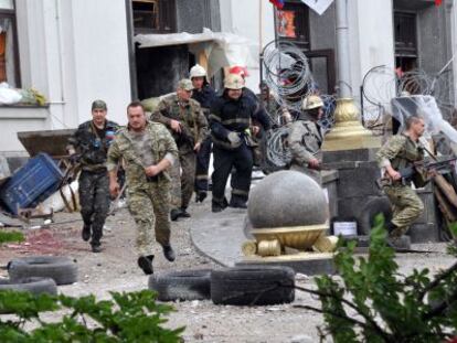 Milicianos prorrusos y bomberos se alejan de la sede regional de Donetsk.