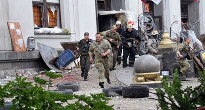 Milicianos prorrusos y bomberos se alejan de la sede regional de Donetsk.