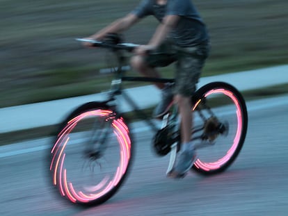 una persona subida en una bici en la calle con luces en los radios.