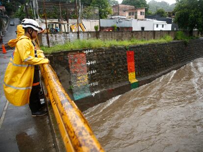 Un trabajador de protección civil inspecciona el caudal de un río en San Salvador, este domingo.
