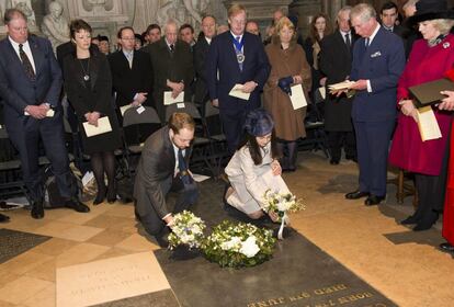 Camila, duquesa de Cornualles, y su esposo, el príncipe Carlos de Inglaterra, observan como Rob, el tataranieto de Charles Dickens, y Rachel Dickens Green, hija del tataranieto del escritor, dejan flores sobre la tumba de su antepasado, durante la ceremosnia del dicentenario de su nacimiento en la abadía de Westminster.