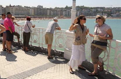 Una pareja de turistas se fotografía en La Concha de San Sebastián.