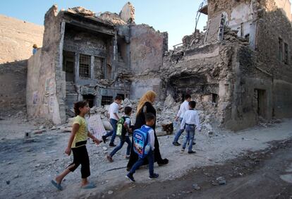 Una mujer camina con sus hijos el primer día del período escolar en la ciudad vieja de Mosul (Iraq).