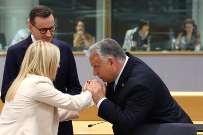 Viktor Orbán besa la mano de la primera ministra italiana, Giorgia Meloni, en presencia del primer ministro de Polonia, Mateusz Morawiecki, este jueves en Bruselas.