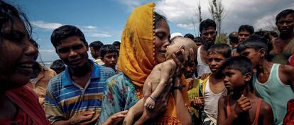 Uma mulher chora enquanto segura seu filho que morreu afogado quando um bote em que estavam virou antes de chegar a Bangladesh.