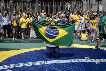 Un seguidor del presidente alza al cielo una bandera brasileña mientras está hincado sobre otra, durante las celebraciones por el día de la Independencia en Belo Horizonte.