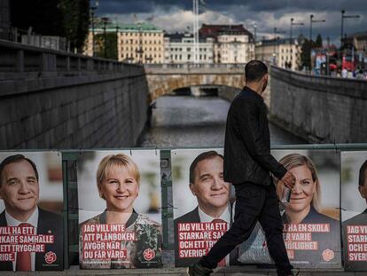 Un hombre camina junto a los carteles electorales de los ministros Stefan Loefven, Magdalena Andersson y Margot Wallstrom.