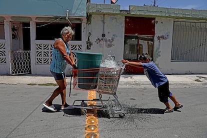 Una mujer y un niño transportan contenedores de agua en un carro de supermercado en Apodaca, Nuevo León, en 2022.