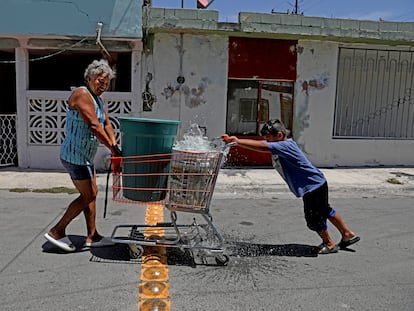 Una mujer y un niño transportan contenedores de agua en un carro de supermercado en Apodaca, Nuevo León, en 2022.