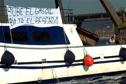 Un centenar de embarcaciones de pesca de toda Cataluña participan en la paralización de las dos bocanas del puerto de Barcelona, que está totalmente cerrado a las entradas y salidas de buques de pasajeros y mercancías desde hace 14 horas. Se prevé que el cierre afecte a lo largo del día a unas 23 entradas y 35 salidas de buques. En la foto, uno de los barcos en huelga, con una pancarta reivindicativa.