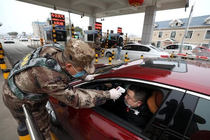 Un miembro de la milicia verifica la temperatura corporal de un conductor en un vehículo en Wuhan, la provincia central china de Hubei, el 23 de enero.
