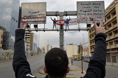Un hombre levanta los brazos en señal de victoria frente a dos manifestantes que sostienen una bandera nacional libanesa durante las protestas en Beirut (Líbano), el 17 de enero.