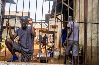 Un prisionero de la cárcel central de Freetown se agarra a los barrotes de un patio. 