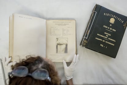 Una investigadora hojea uno de los tomos del archivo del Museo Penitenciario Paulista, en la imagen una de las fichas.
