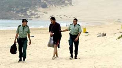 Dos guardias civiles, junto a un inmigrante irregular interceptado ayer en la playa de Bolonia.