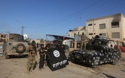 Uns iraquians mostren victoriosos una bandera de l'ISIS després de recuperar Ramadi.