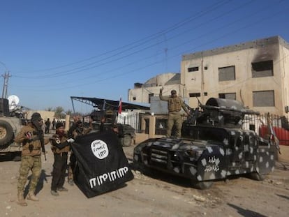 Uns iraquians mostren victoriosos una bandera de l'ISIS després de recuperar Ramadi.