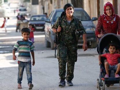 Una miliciana kurda, junto a una familia, en Kobane.