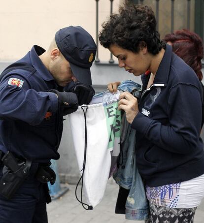 Un policía inspecciona el interior de una bolsa a una manifestante en la plaza de Neptuno.