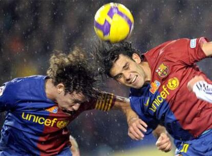 Puyol y Márquez saltan a la vez para intentar despejar de su área el balón.