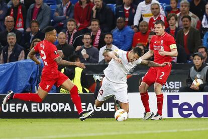 El jugador del Sevilla Vitolo cae ante Nathaniel Clyne y James Milner del Liverpool durante el partido por la final de la Liga Europa.