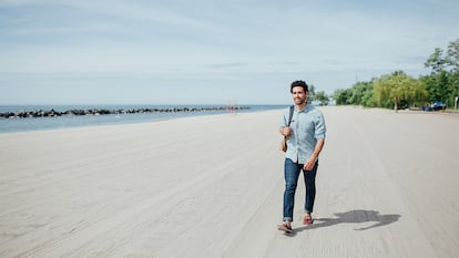 Un hombre caminando por la playa con mocasines