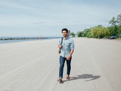 Un hombre caminando por la playa con mocasines