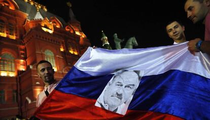 Seguidores de la selección rusa de fútbol celebran en Moscú la victoria contra España en el Mundial con una bandera del país y un retrato del entrenador del equipo, Stanislav Cherchesov.