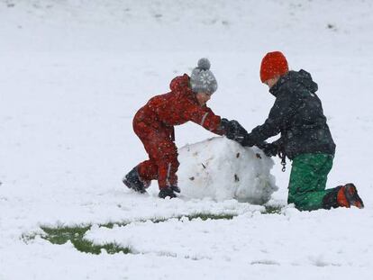 Una familia construye un muñeco de nieve en un parque en el norte de Londres (Inglaterra).