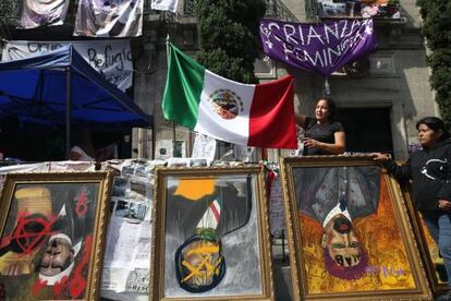 Mujeres muestran cuadros intervenidos fuera de la Comisión Nacional de Derechos Humanos en Ciudad de México.